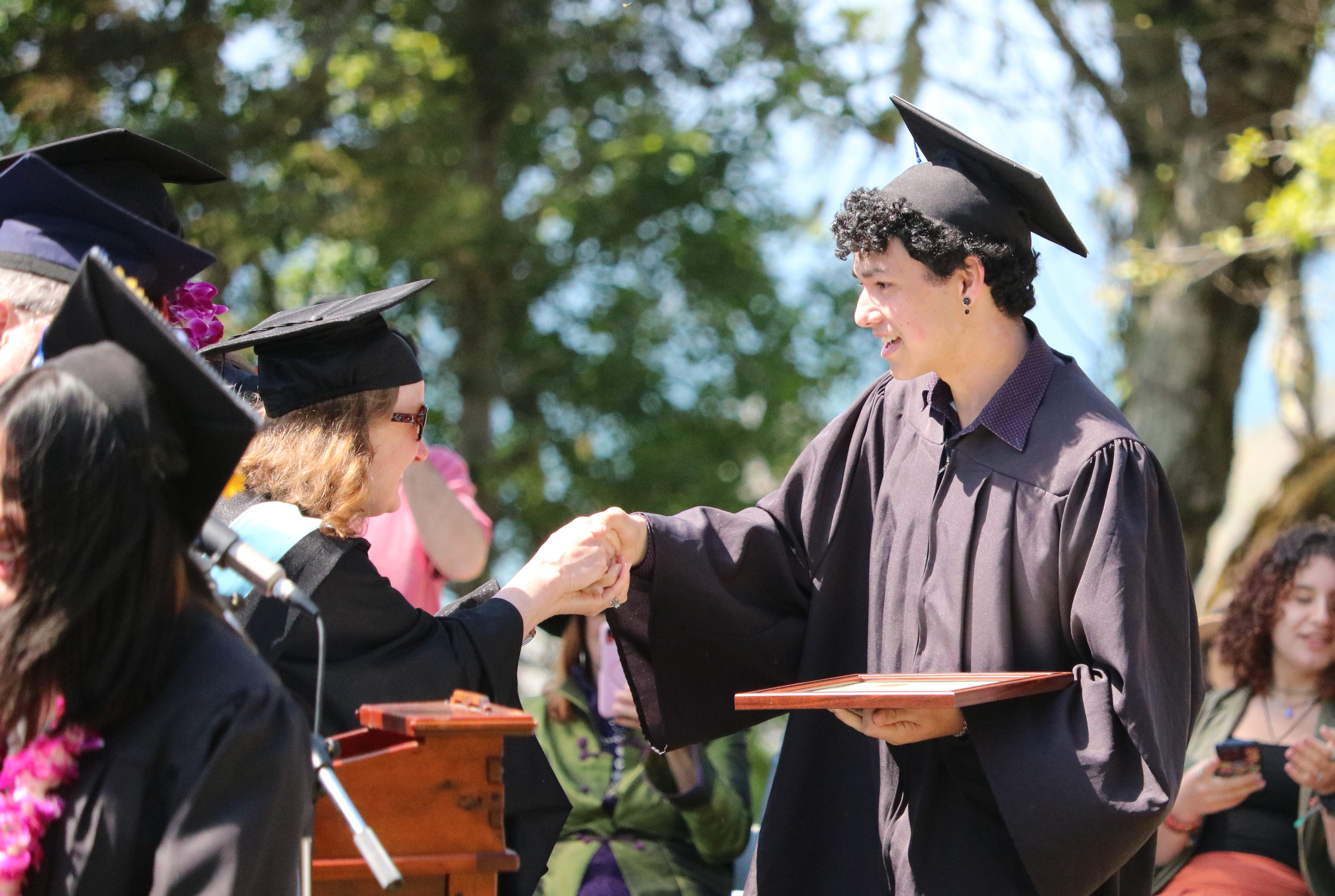 High school graduate shakes hands with administrator and receives his diploma.